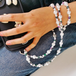 Detail of a floral beaded phone strap with white pearls and silver hollow metal beads