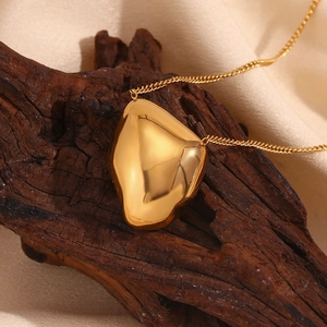 Macro shot of gold sun and moon pendant on O-chain necklace over dark wood and satin