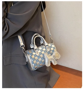 Detail view of mini cylinder pillow bag featuring blue denim and silver checkerboard pattern
