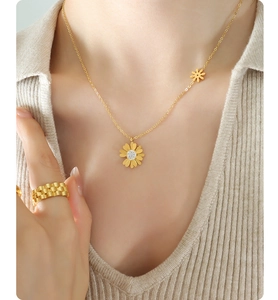 Vista detallada del collar con colgante de margarita y anillo de oro con circón