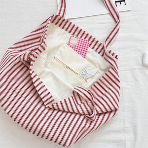 Close-up of red striped canvas tote bag showing interior lining and zipper pocket