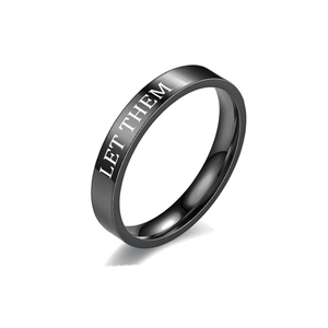 Close-up of black titanium steel ring featuring 'LET THEM' engraving on flat band