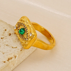 Gros plan d'une bague vintage dorée avec pierre malachite verte et cristaux étincelants