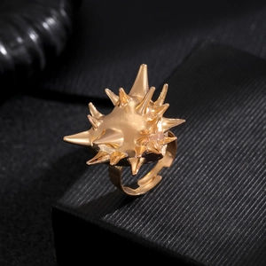 Detailed view of punk spike gold-toned adjustable ring on a black textured background