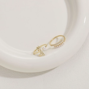 Detail of 14K gold-plated rings set featuring 'Love' script, pearls, and zircons on ceramic