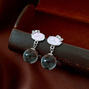 Macro shot of silver needle cat earrings with sparkling bow and grey glass bead pendant