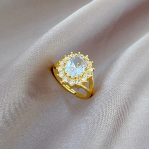 Close-up of luxury gold adjustable ring with oval clear stone on purple silk fabric