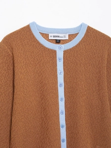 Detail von Strickjacke in Karamell mit kontrastierendem himmelblauem Rundhals und Knöpfen
