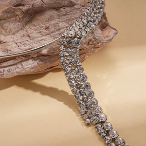 Close-up of triple-row rhinestone necklace with silver finish on natural stone background