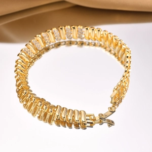 Detailed view of golden copper bracelet with zircons and fold-over clasp on gold satin