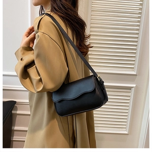 Detail view of black PU leather underarm bag with wave-shaped flap and gold hardware