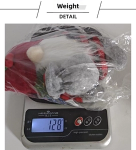 Detail shot showing the weight of the knitted cherry gnome plush toy at 128 grams