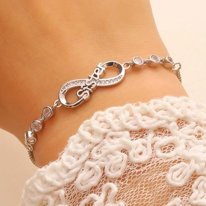 Macro detail of infinity sister bracelet with micro-pave cubic zirconia on lace background