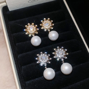 Detailed macro of snowflake earrings with small diamonds and round pearls in a velvet box