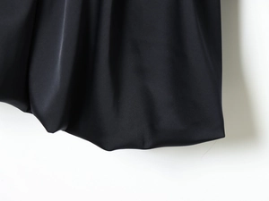 Détail du tissu en satin noir haut de gamme montrant un drapé lisse et éclat soyeux