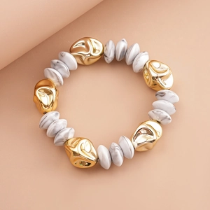 Detail of irregular gold metal beads and white marble beads on a beaded bracelet