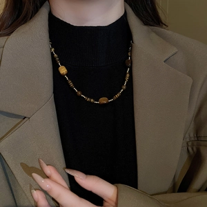 Gros plan du collier en perles d'oeil de tigre marron avec détails dorés sur mannequin