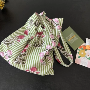 Detailed view of floral canvas tote bag with pink blossoms and green stripes on dark background