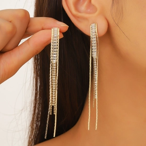 Close-up of elegant gold long tassel earrings with sparkling rhinestones on a model
