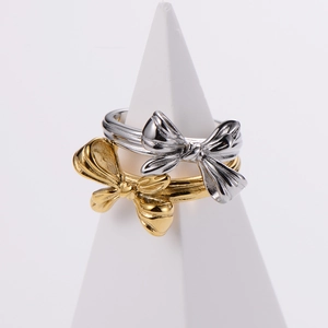 Minimalist gold and silver bow shaped irregular rings displayed on geometric pedestals