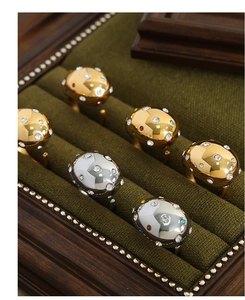 Close-up of gold and silver teardrop rings with colored stones on velvet lining