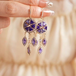 Close-up of vintage gold tassel earrings with purple gems and zircon star patterns