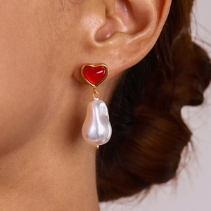 Boucles d'oreilles cœur doré avec perle baroque blanche portées par un mannequin