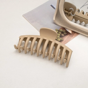 Detailed macro view of a large matte beige shark hair claw clip for thick hair styling