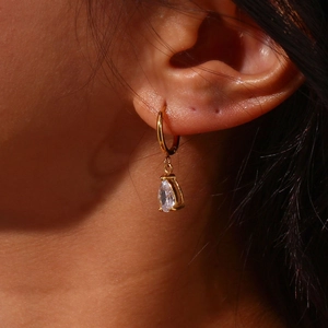 Primer plano de los pendientes de aro dorados con circón en pera sobre modelo mujer