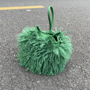 Detailed view of green faux shearling bucket bag with drawstring and leather handle