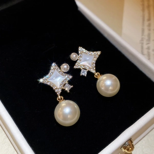 Détail de boucles d'oreilles en forme d'étoile avec nacre et perles sur velours noir