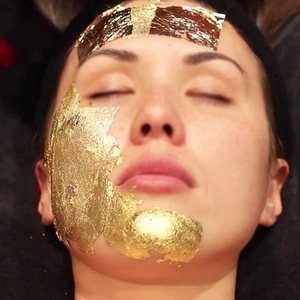 Macro detail of luxury gold foil mask flakes applied on face for skin treatment