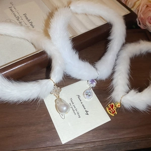 Detail of plush necklaces with pearl, zircon, and red horse charms on dark wooden tray