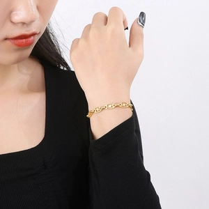 Detail of a gold stainless steel oval link chain bracelet worn on a woman wrist