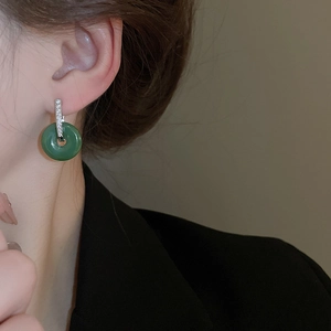 Detailed view of elegant green jade Ping'an buckle earrings worn on the ear
