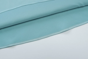 Detailaufnahme der sauberen Saumnähte und tiffanyblauen Stofftextur an einem rückenfreien Kleid