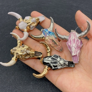 Five colorful acrylic bull skull pendants held in palm showing various stone textures