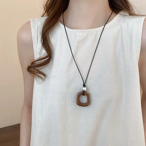Detail of square dark brown wood pendant necklace with silver bead on black cord