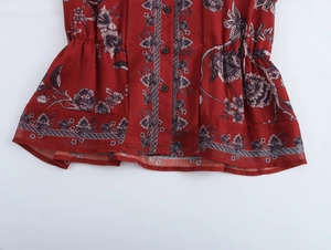 Close-up of red chiffon top with floral print, black buttons, and ruffle waist detail