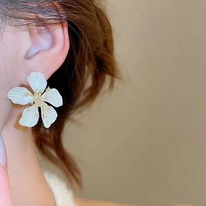 Close-up of elegant cream flower stud earring with gold texture worn on model ear
