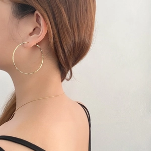 Side view of model wearing large minimalist golden hoop earrings with high polish finish