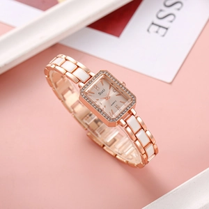 Detailed macro view of rose gold square watch with crystal bezel and white ceramic band