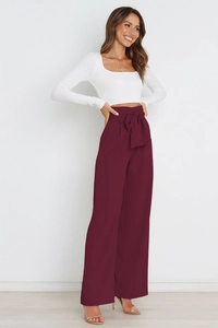 Detail view of high waist wide leg trousers with a stylish waist bow in wine red fabric