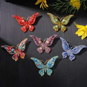 Detailed view of six colorful crystal butterfly brooches arranged on a black striped surface