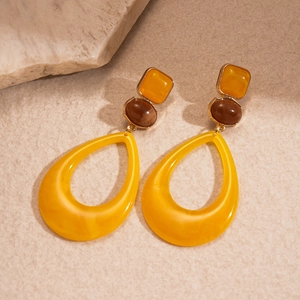 Macro view of geometric resin drop earrings with yellow and brown stones on stone