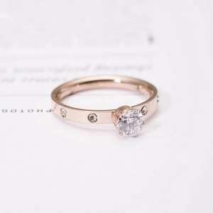 Macro detail of rose gold ring featuring six-prong setting and small round diamonds