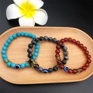 Three-piece turquoise and evil eye beaded bracelets with gold crowns on a wooden tray