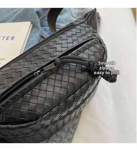 Detailed view of the smooth metal zipper and woven leather texture on this black chest bag