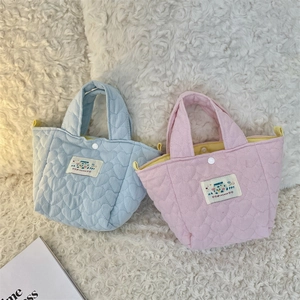 Detail of quilted cotton tote bag featuring heart stitching and happy patch embroidery