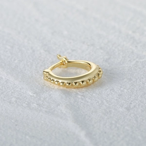 Macro shot of minimalist gold S925 sterling silver hoop earring with beaded texture